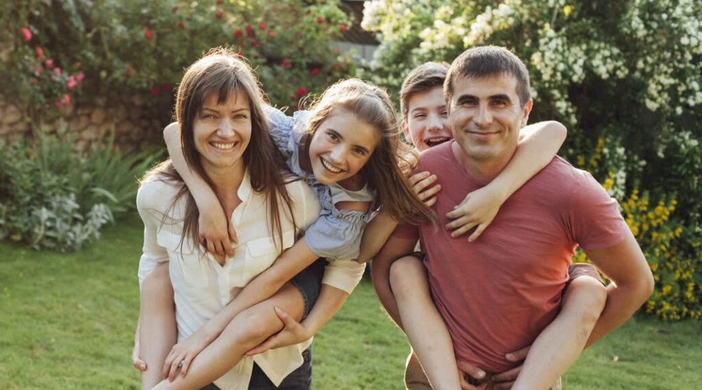 smiling parents with their children outside giving them a piggy back ride