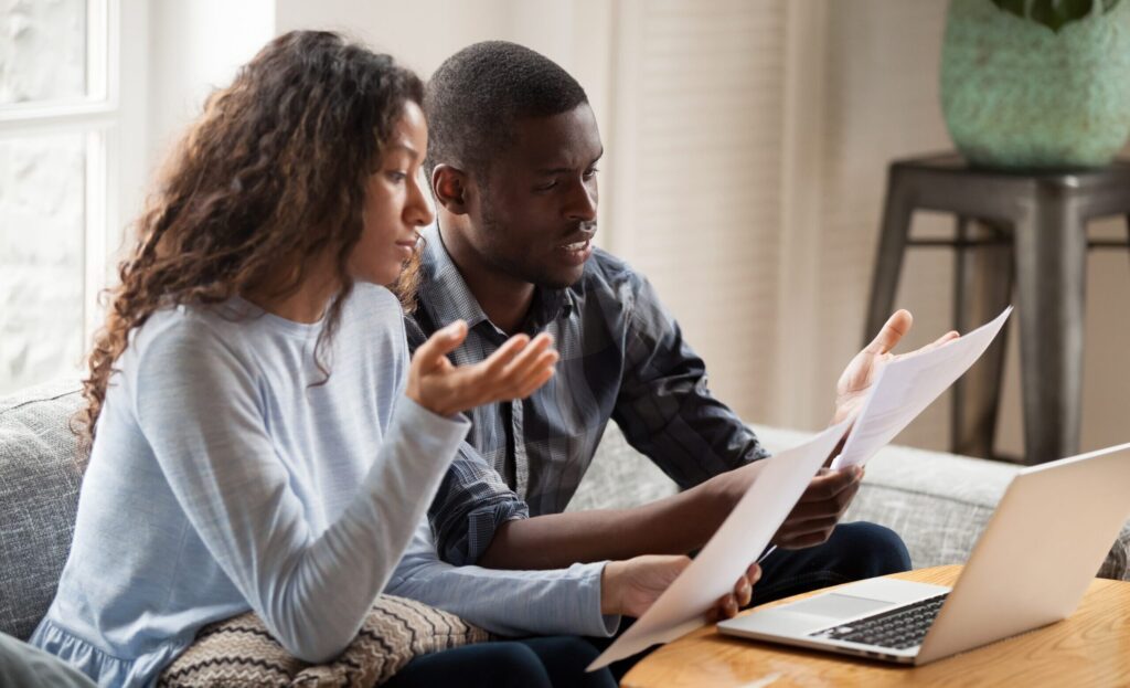 wife and husband stressing over bills on the couch